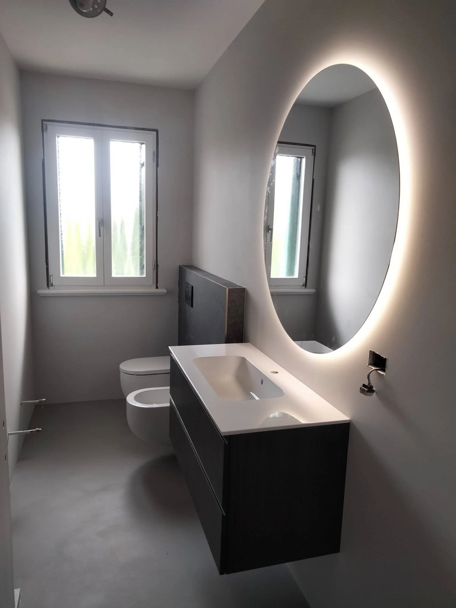 Bagno con mobile sospeso e specchio ovale retroilluminato